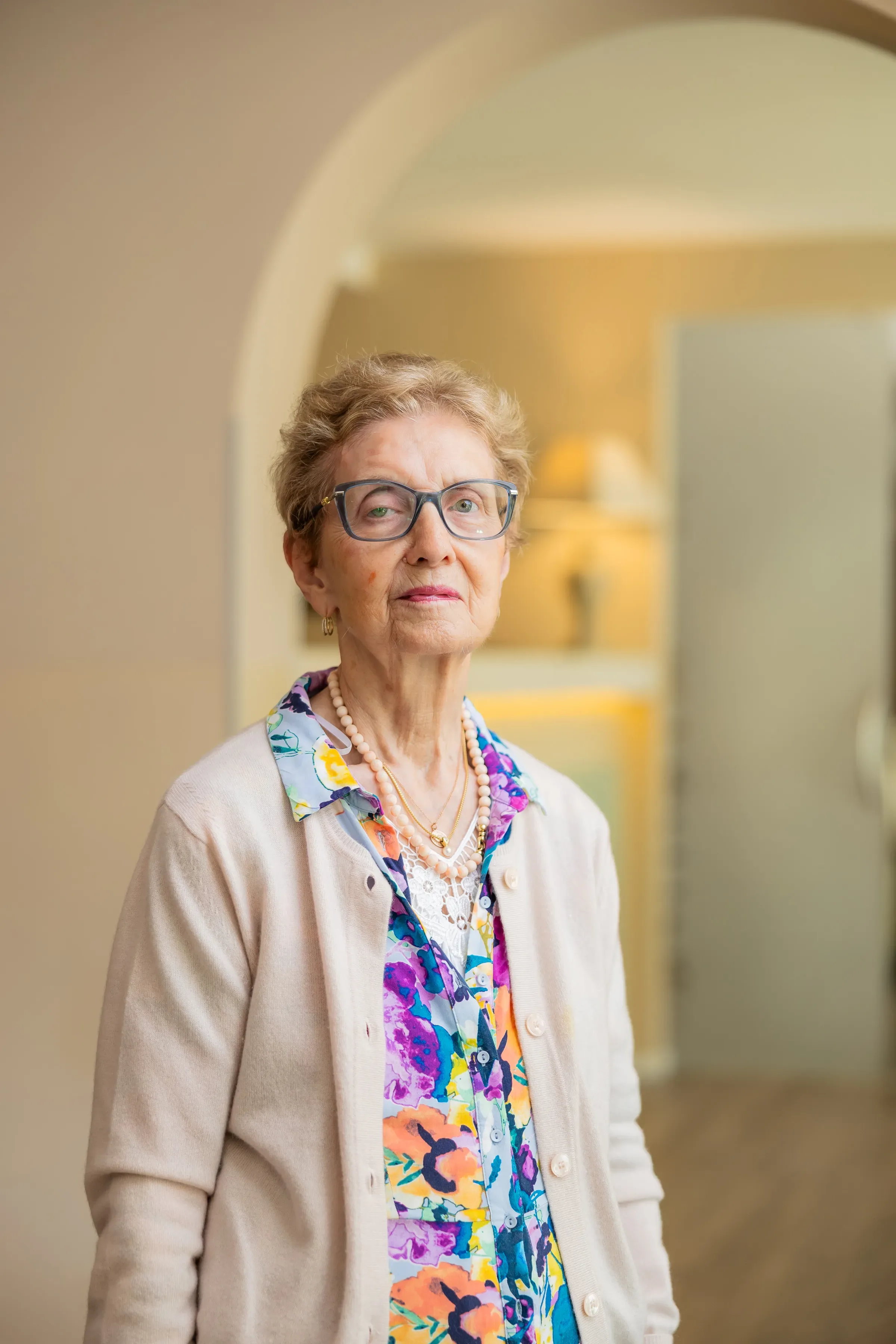 Anziana con occhiali e cardigan in un ambiente luminoso