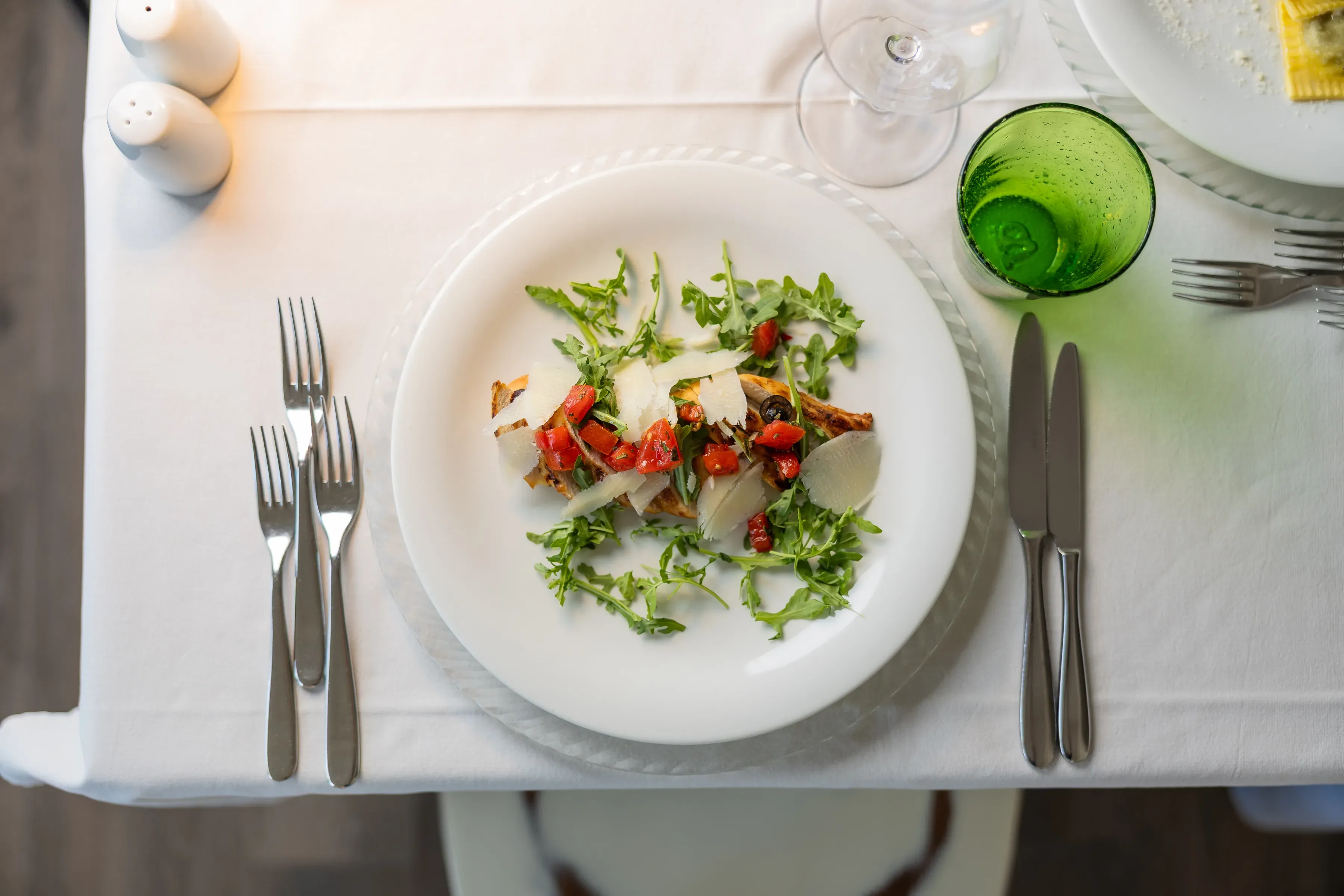 Bruschetta con rucola, pomodorini e scaglie di formaggio su piatto bianco
