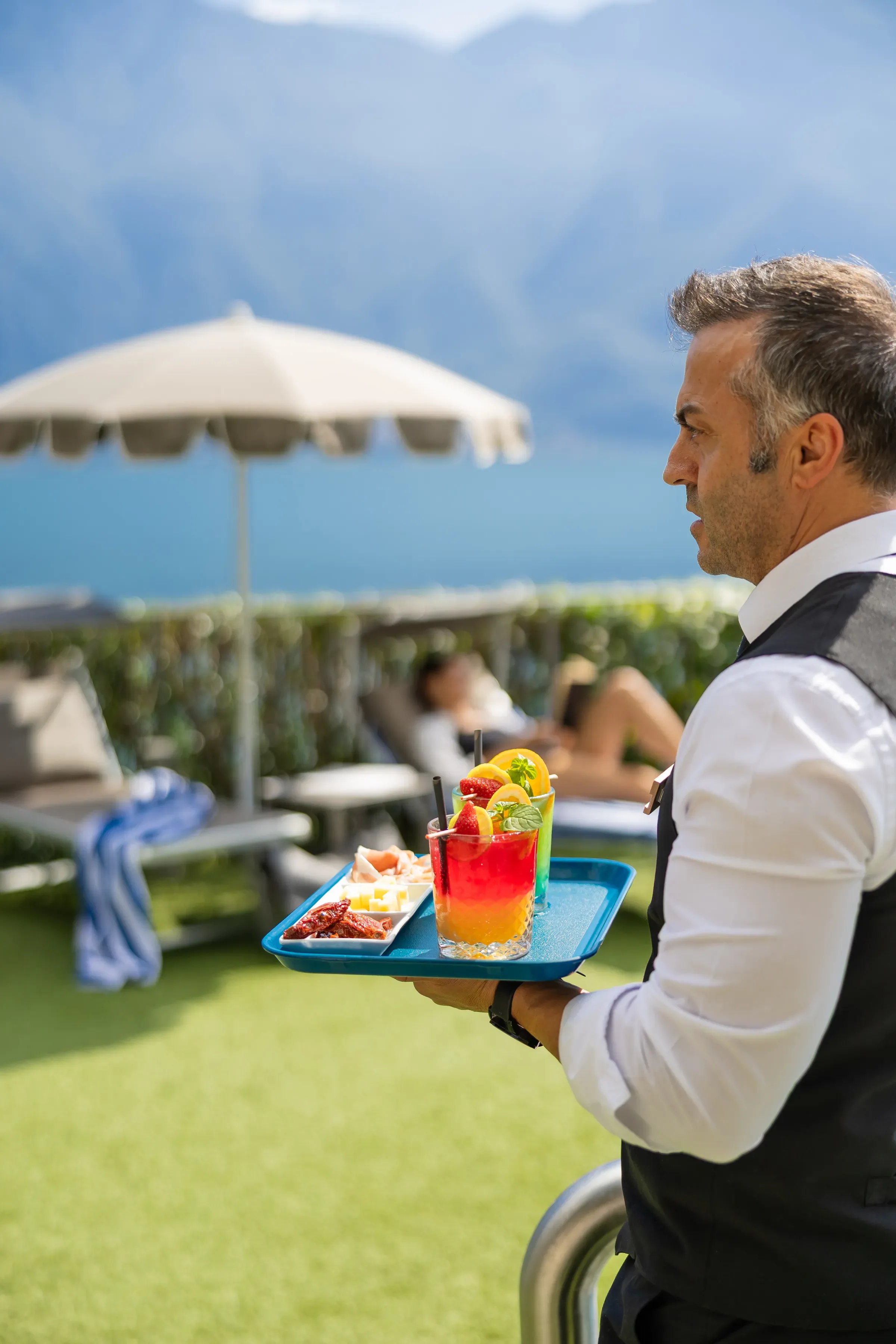 Cameriere serve cocktail colorati in un resort sul lago