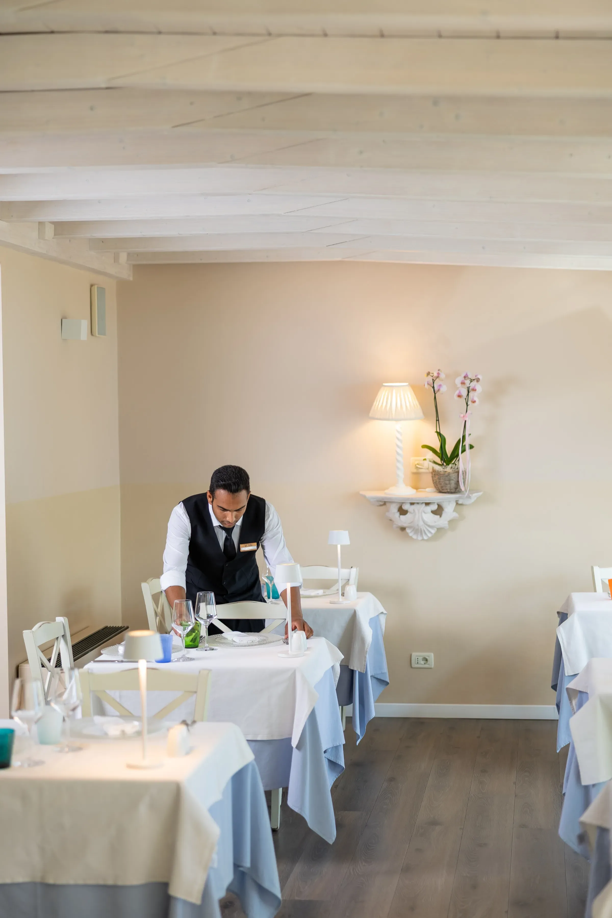 Cameriere che sistema un tavolo in un elegante ristorante