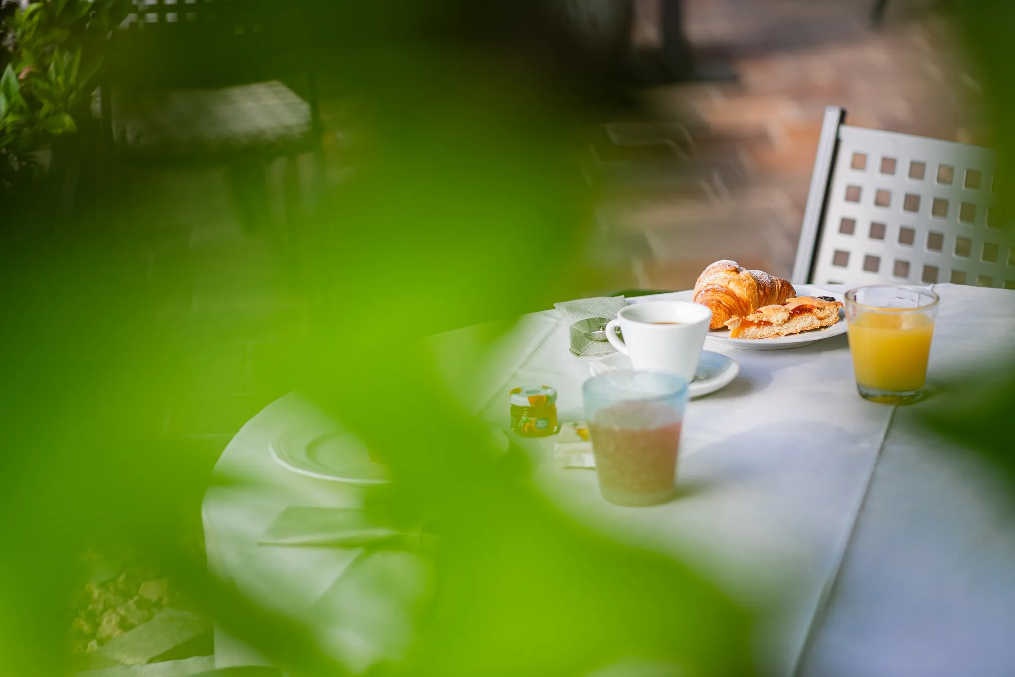 Colazione all'aperto con cornetto, succo d'arancia e caffè su tavolo bianco