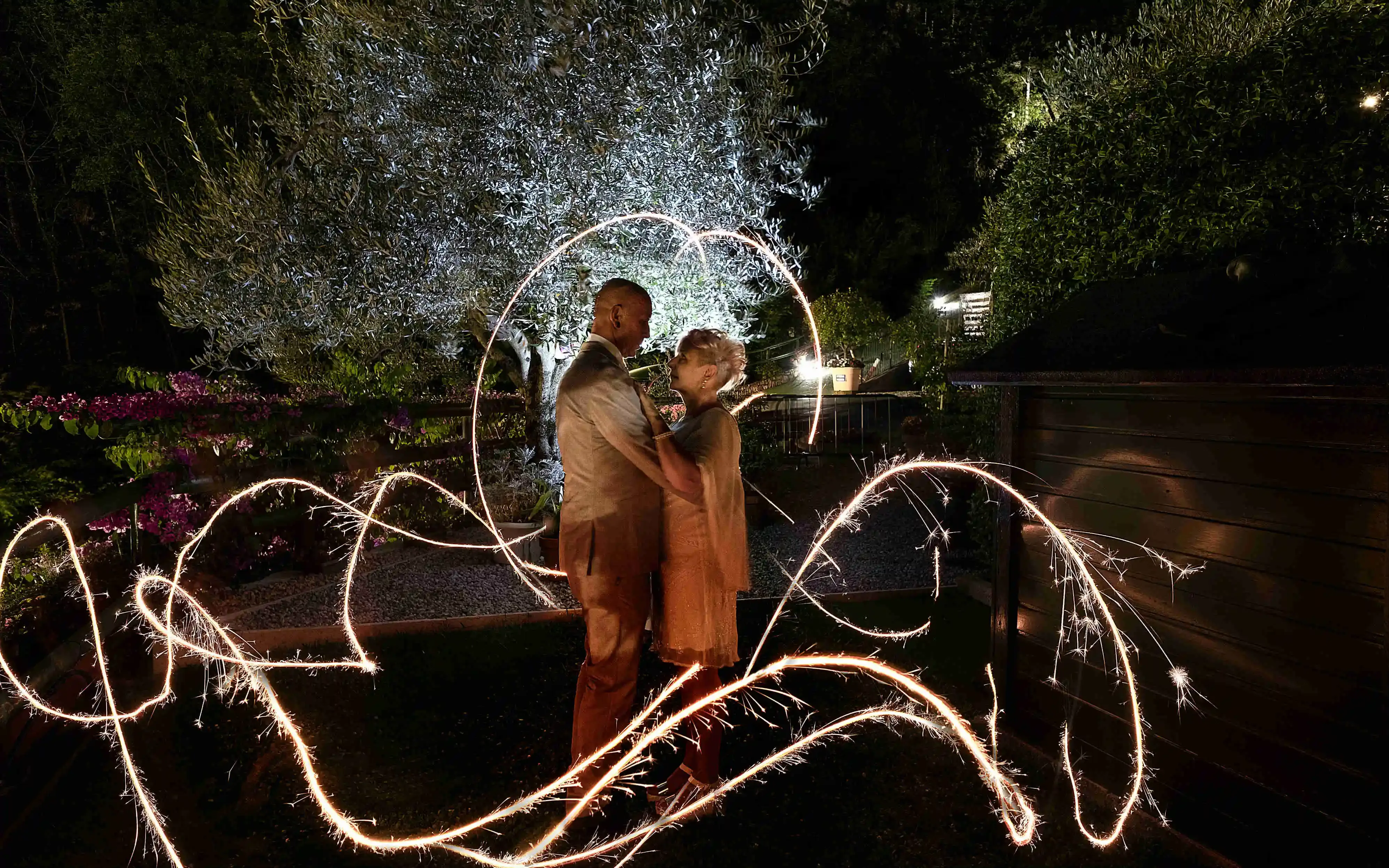 Coppia romantica abbracciata con luci scintillanti in un giardino di notte