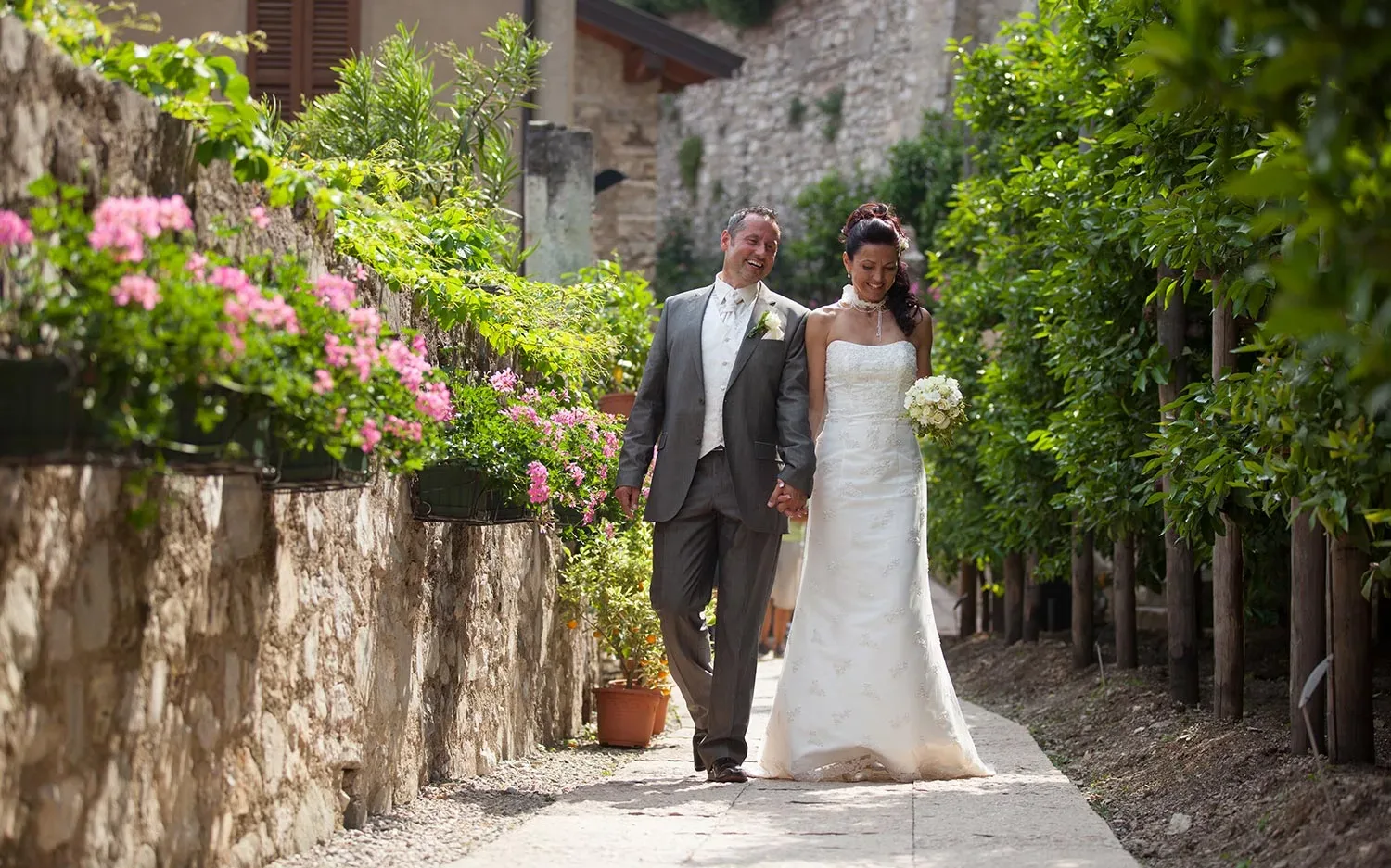 Coppia di sposi felici che cammina in un giardino fiorito