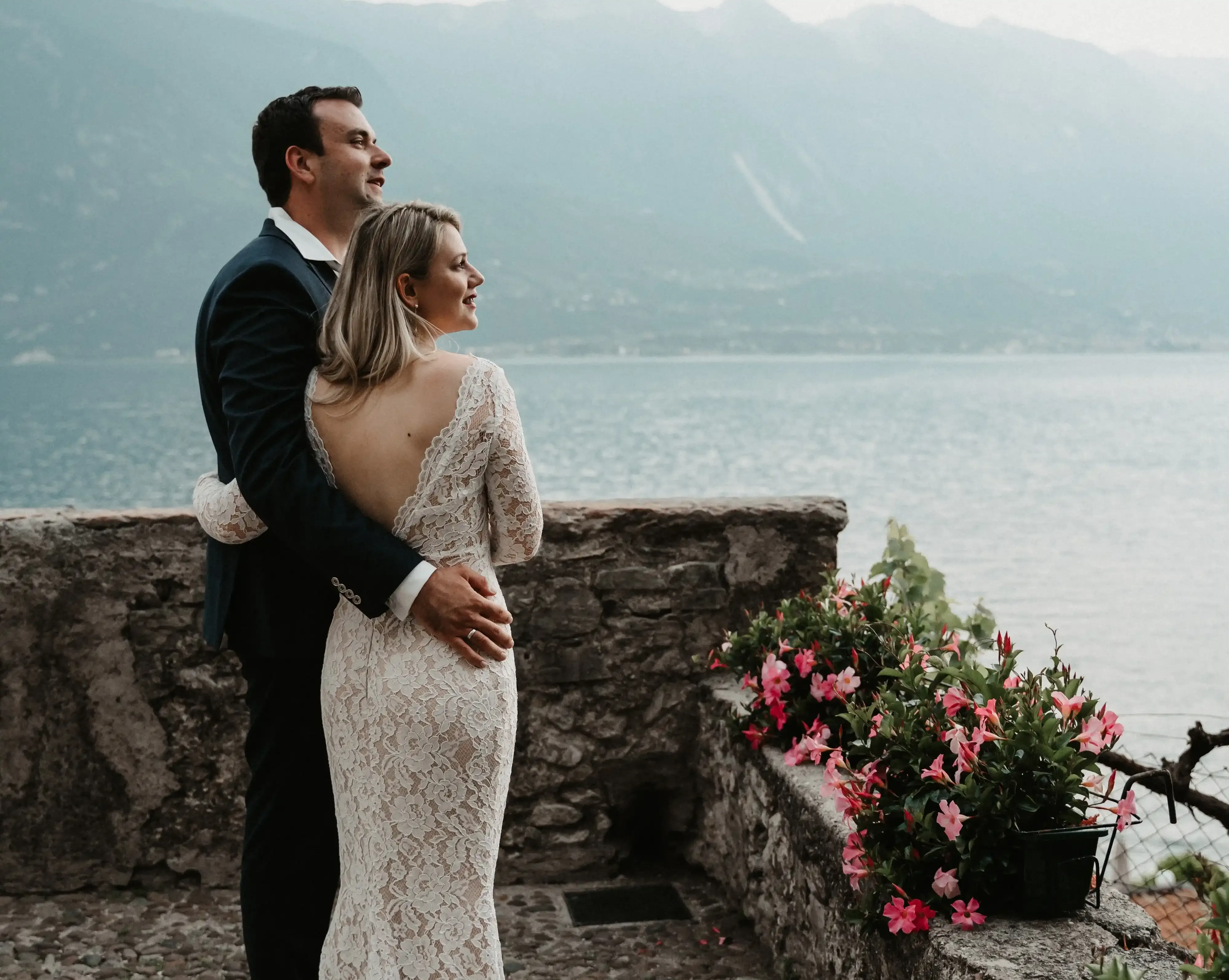 Coppia di sposi abbracciati con vista lago e montagne