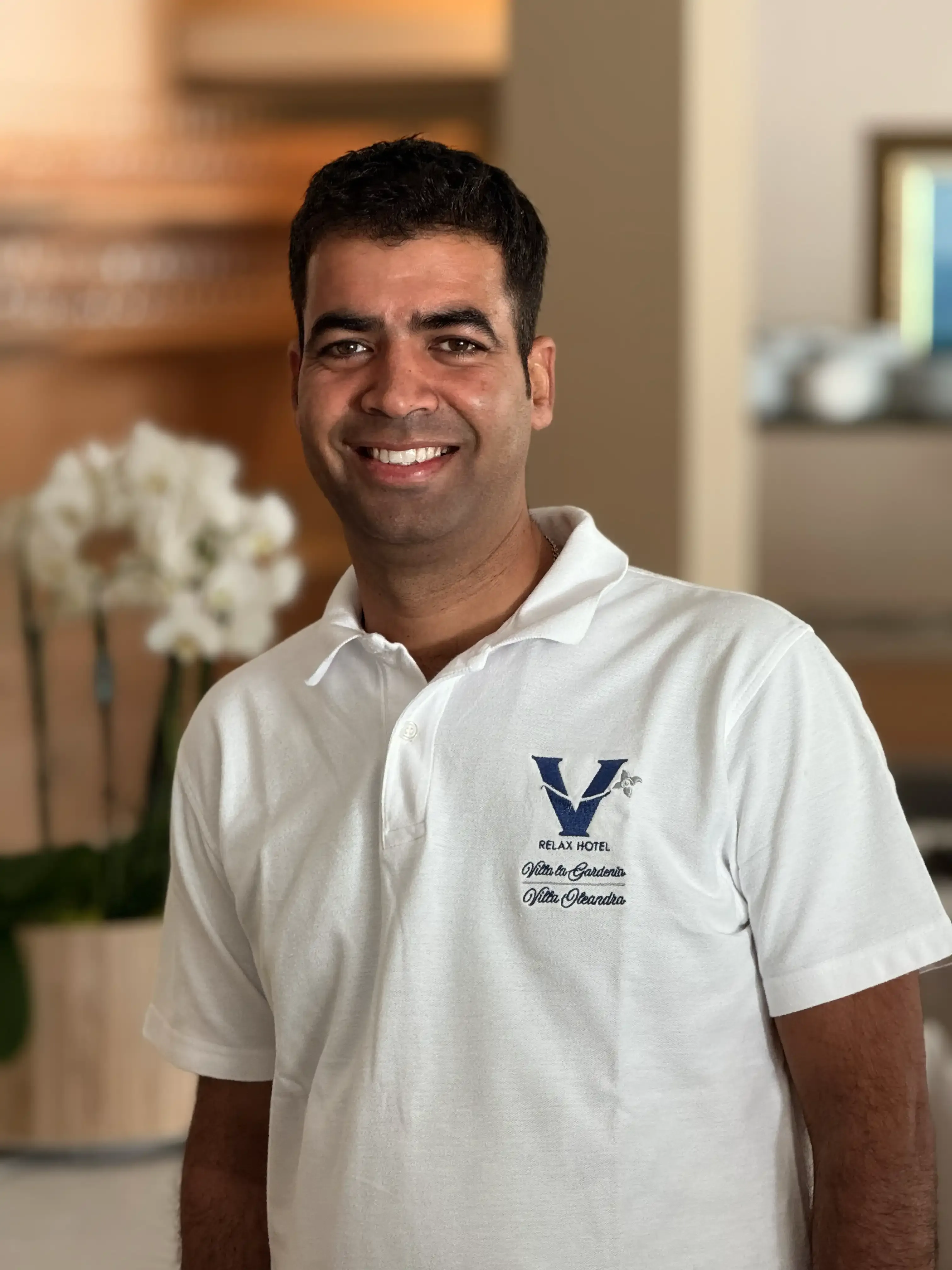 Dipendente dell'hotel con polo bianca sorride nella hall