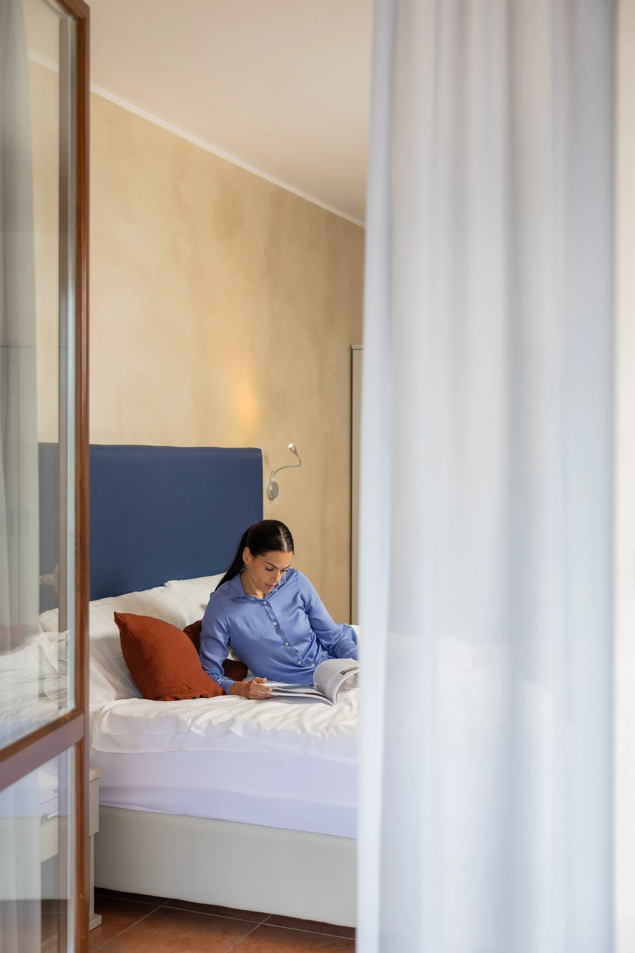 Donna che legge un libro a letto in una stanza accogliente