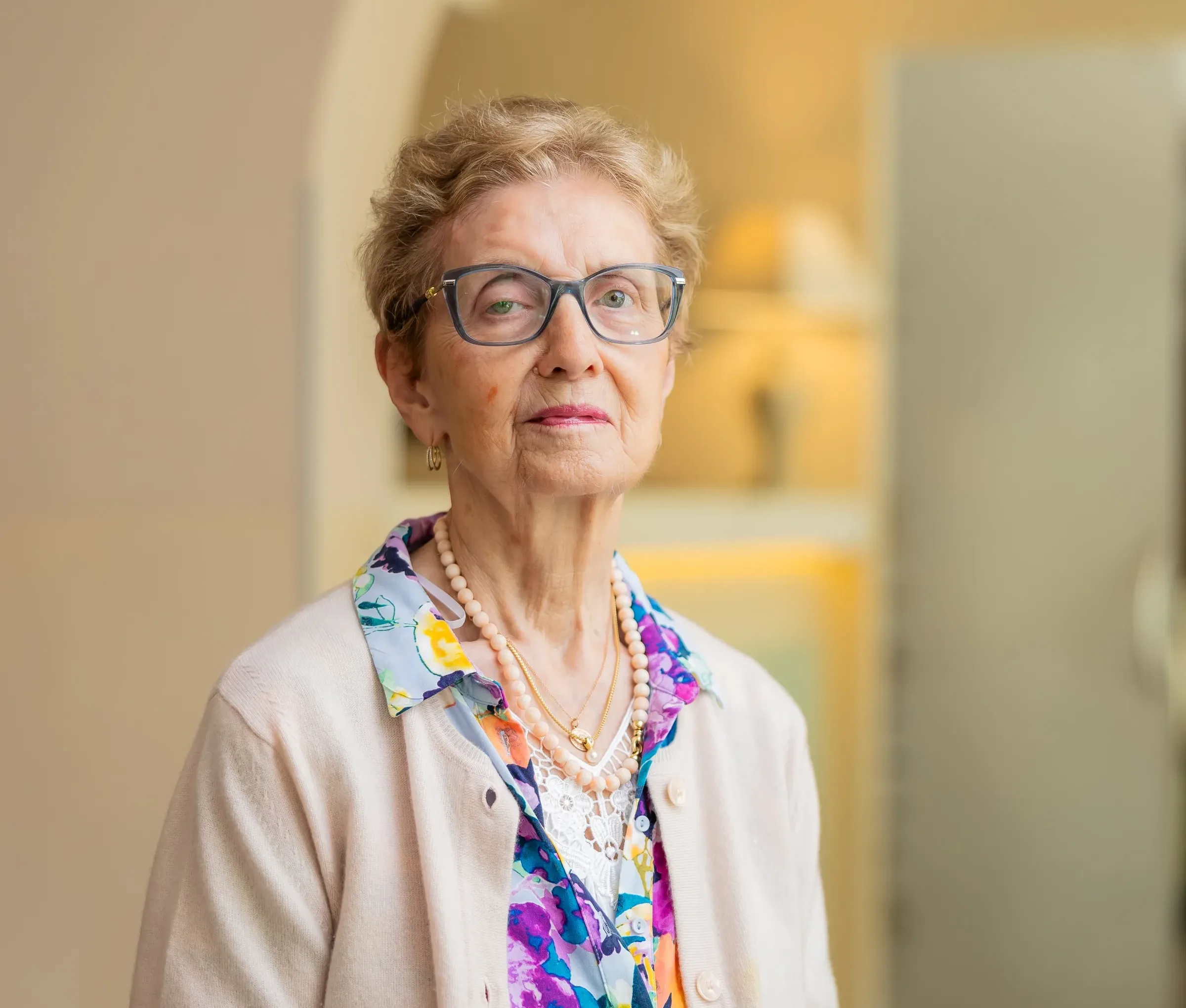 Elderly woman with glasses and floral shirt