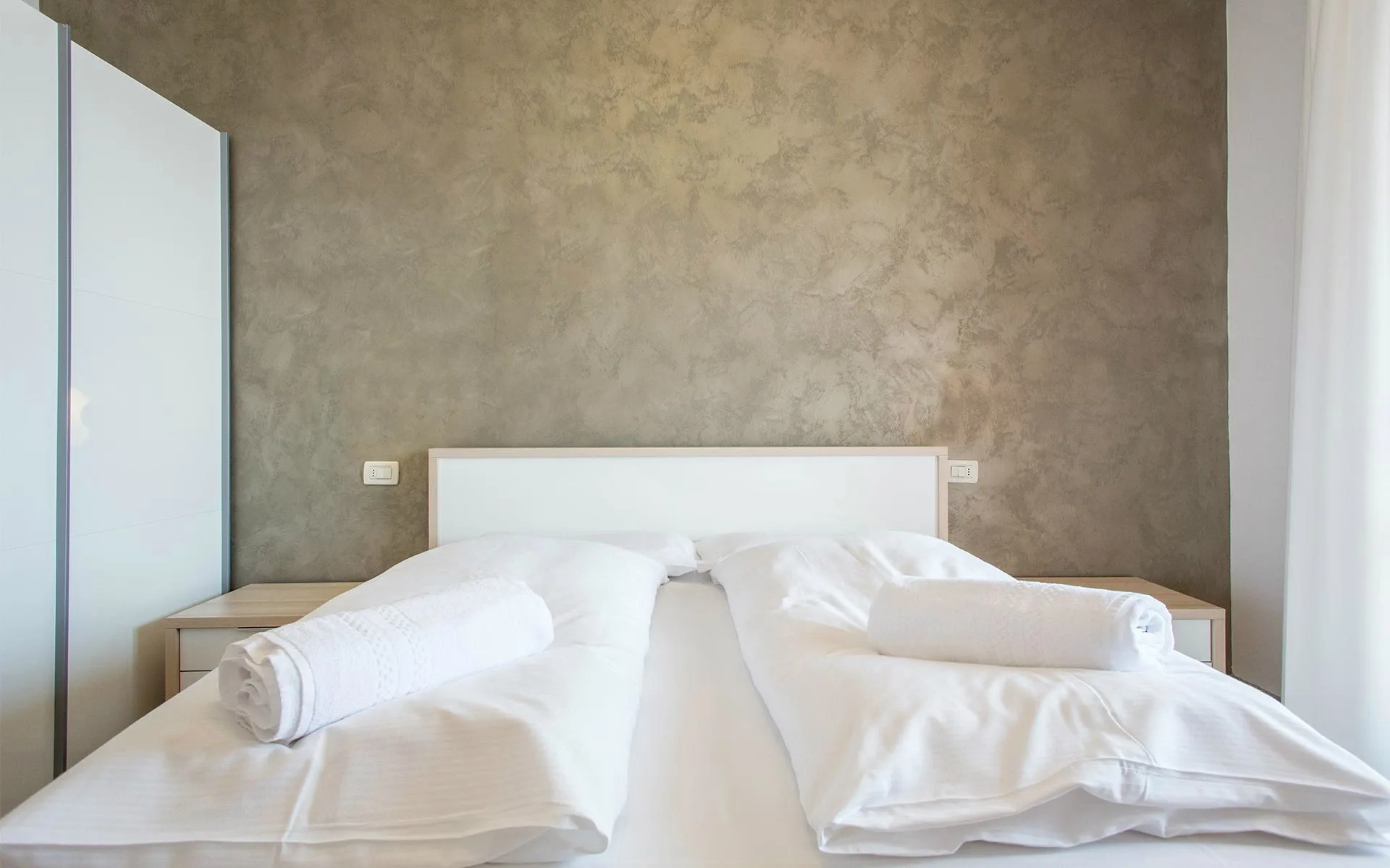 Letto matrimoniale con biancheria bianca e asciugamani arrotolati