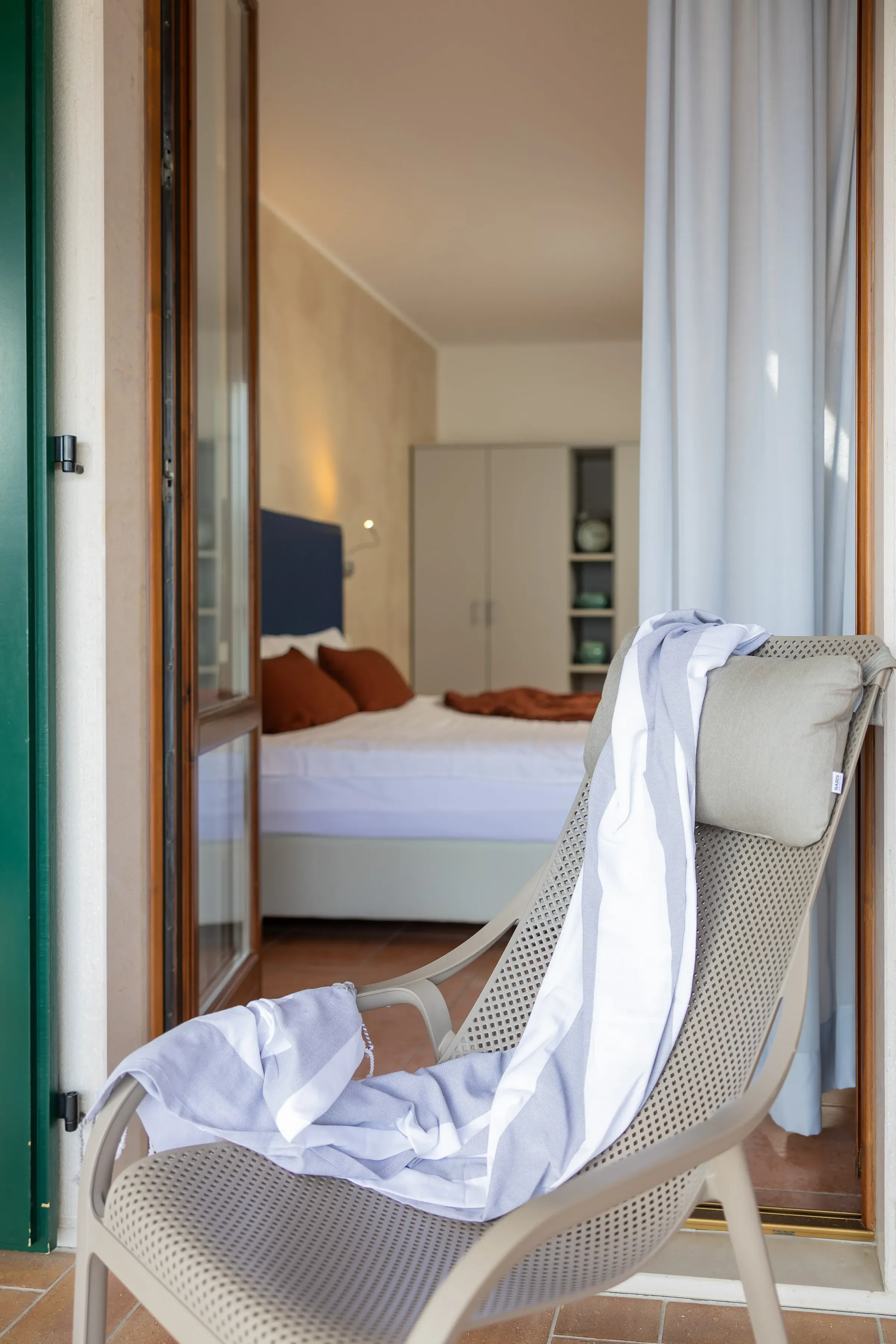 Poltrona su terrazza davanti a una camera da letto accogliente