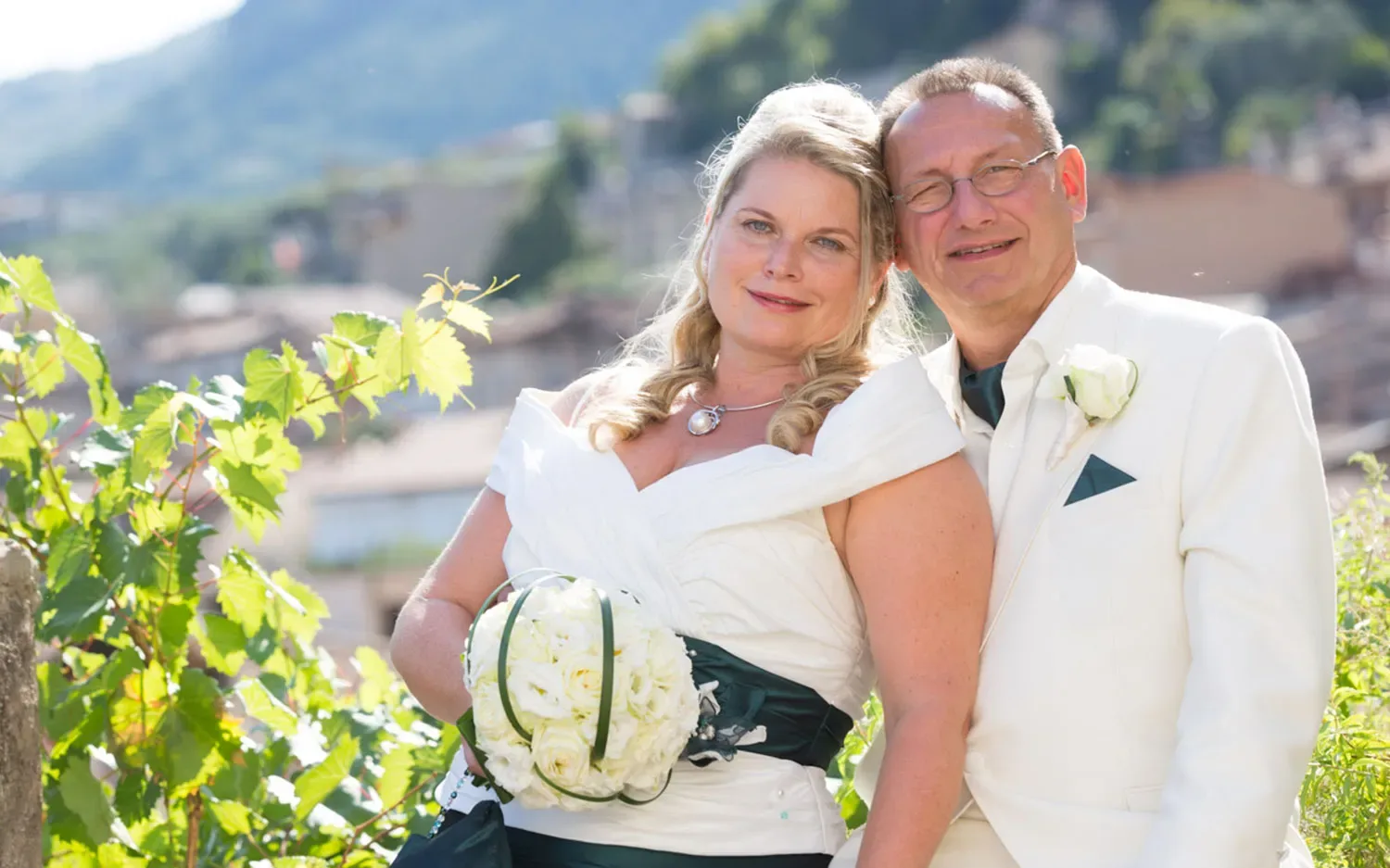 Sposa e sposo sorridenti in abiti eleganti all'aperto