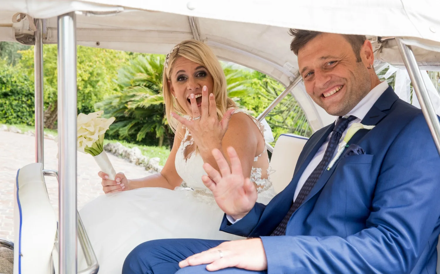 Sposa e sposo sorridenti mostrano le fedi nuziali in auto