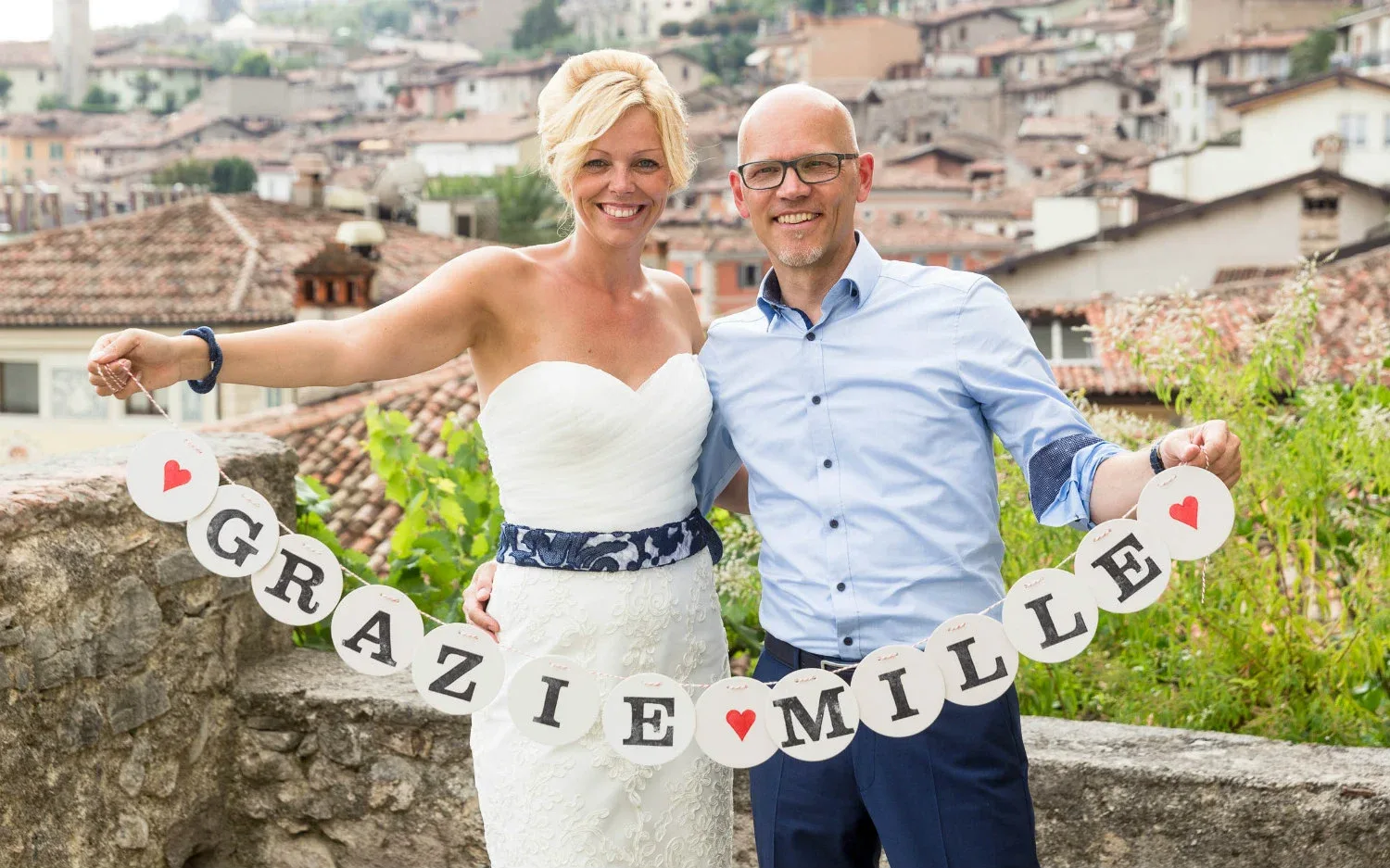 Coppia di sposi felici con striscione 'Grazie mille' dopo il matrimonio