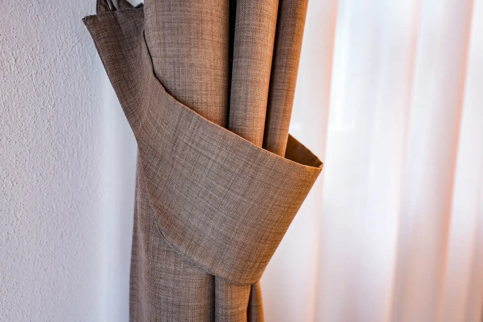 Tenda marrone legata con cinturino vicino a una finestra