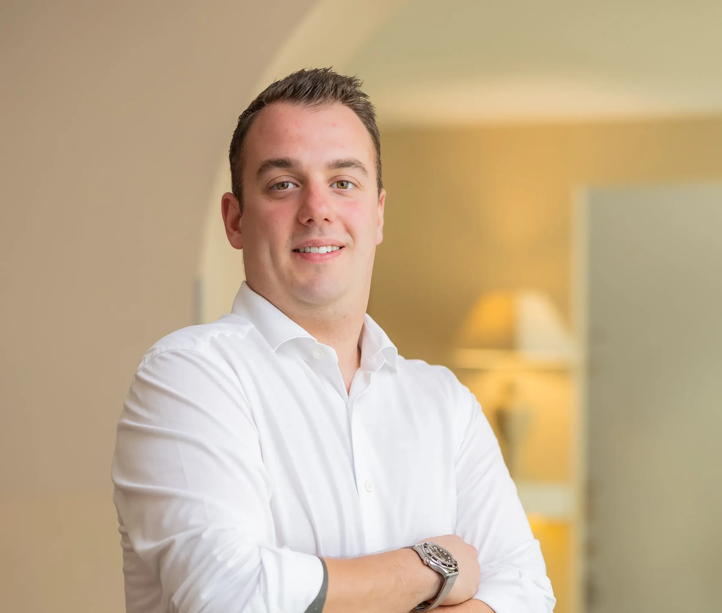 Uomo sorridente con camicia bianca in un ambiente interno