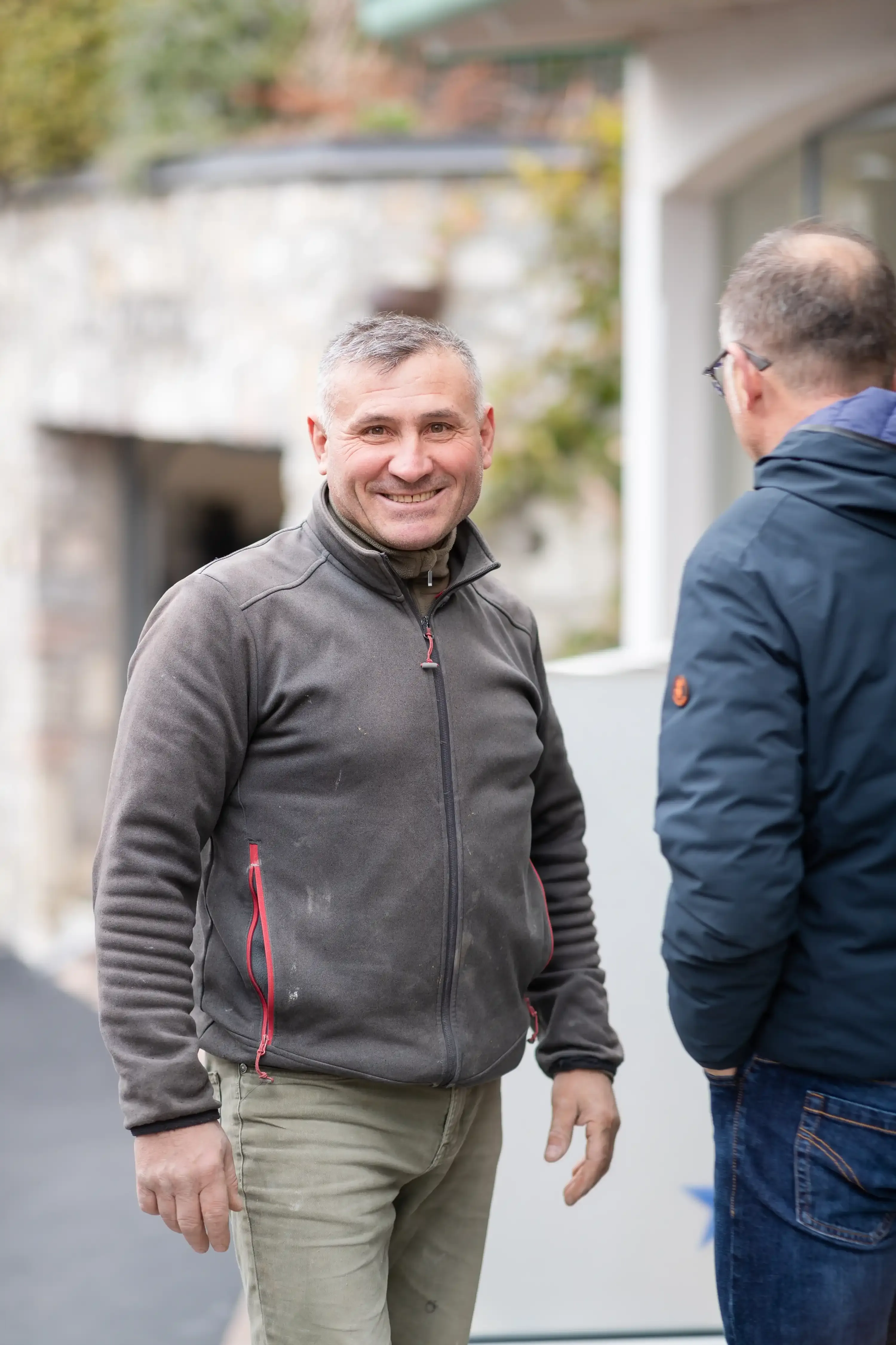 Uomo sorridente che parla con un'altra persona in un cortile