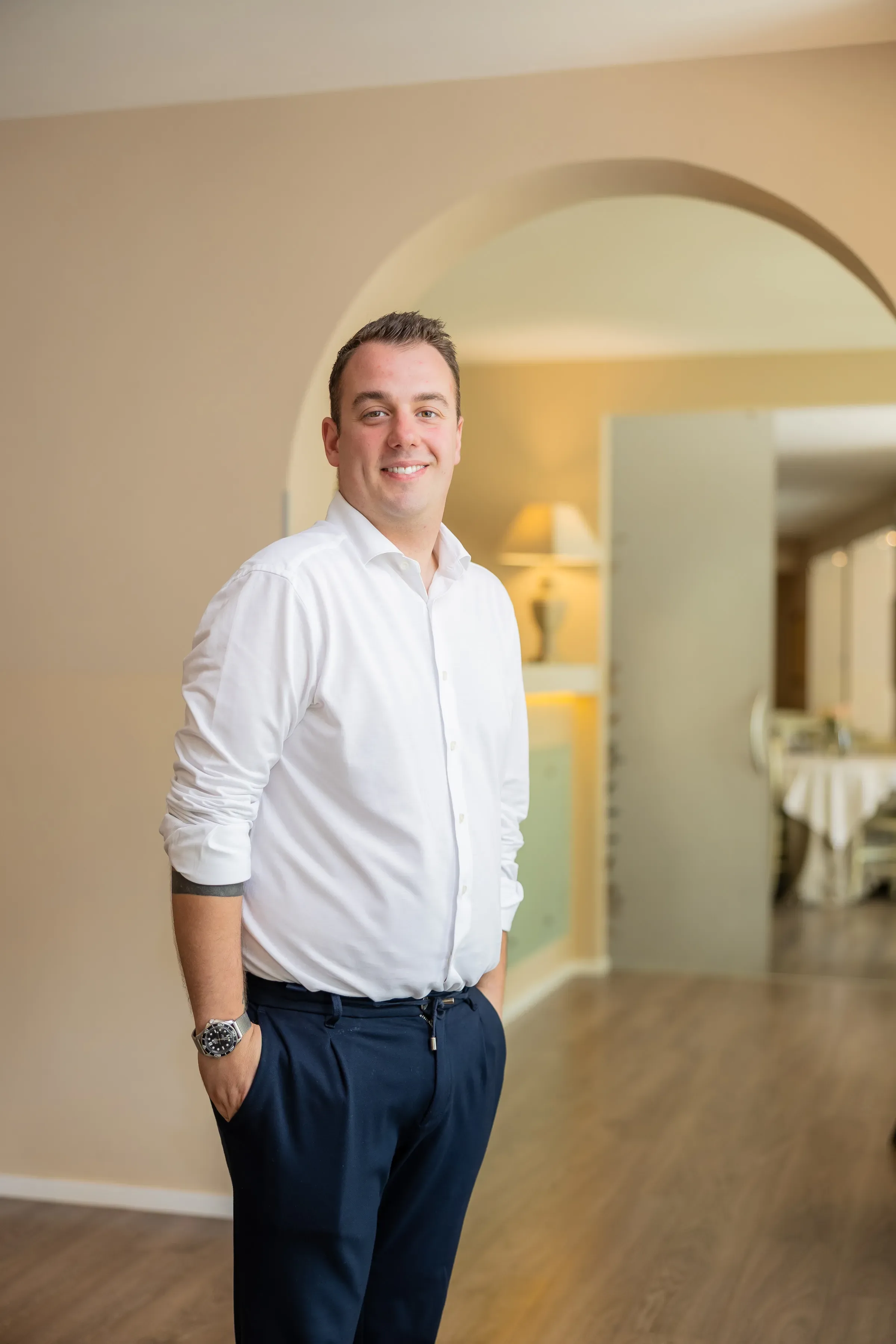 Uomo sorridente con camicia bianca in un ambiente elegante